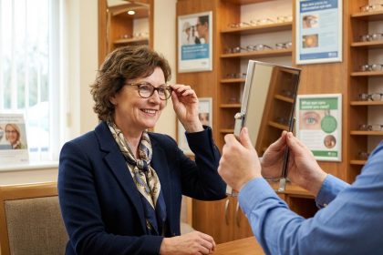 Femme souriante essayant des lunettes dans un cabinet d'opticien
