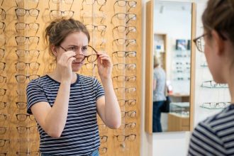 Jeune femme essayant des lunettes dans un magasin d'optique