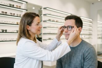 Opticienne ajustant des lunettes sur un client dans un magasin d'optique moderne